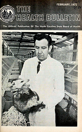Magazine cover depicting a man in a white coat holding an opossum by the nape of its neck.