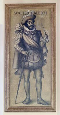 Lee &quot;Walter Raleigh&quot;. Lleva una capa larga, gorguera, pantalones abullonados y medias. Lleva un sombrero con plumas. Sostiene una pipa en su mano izquierda. La punta de la espada descansa contra el suelo y su mano derecha descansa sobre la empuñadura. Tiene barba y bigote.