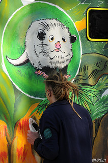 An artist working on a mural for the Leipzig Zoo's Gondwanaland exhibit in May 2011, including a portrait of Heidi the Cross Eyed Opossum. Image from Flickr user Nic Simanek.