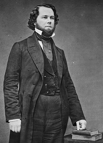 Ruffin. He is younger. He has a thick beard and styled hair. He is wearing a suit.