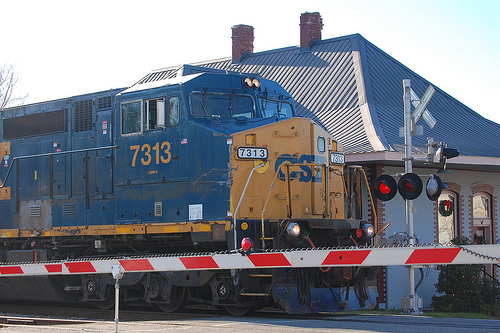 Blue and yellow CSX engine outside of a train station. 