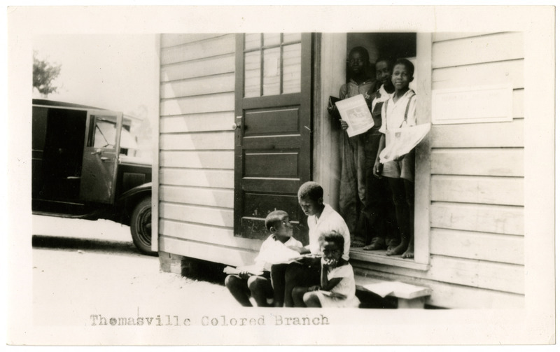 Reads Thomasville Colored Branch where Black children holding books stand or sit in a doorway