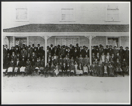 A large group of African Americans of various ages on the porch of a school