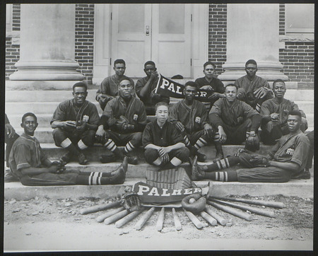 The Palmer baseball team of twelve black men pose with a display of baseball bats, gloves, and balls