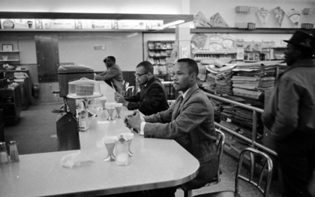 Black men sit quietly at a lunch counter