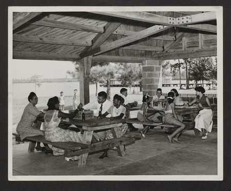 Black families sit at picnic shelters under a shelter at Jones Lake