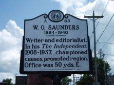 Large metallic marker that reads: &quot;W.O. Saunders 1184-1940. Writer and editorialist. In his The Independent, 1908-1937, championed causes, promoted region. Office was 50 yds. E.&quot;