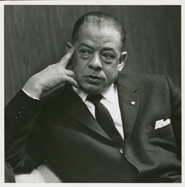 Wheeler. He is depicted wearing a suit and tie. He has oiled hair and looks to be about 35 or 40.