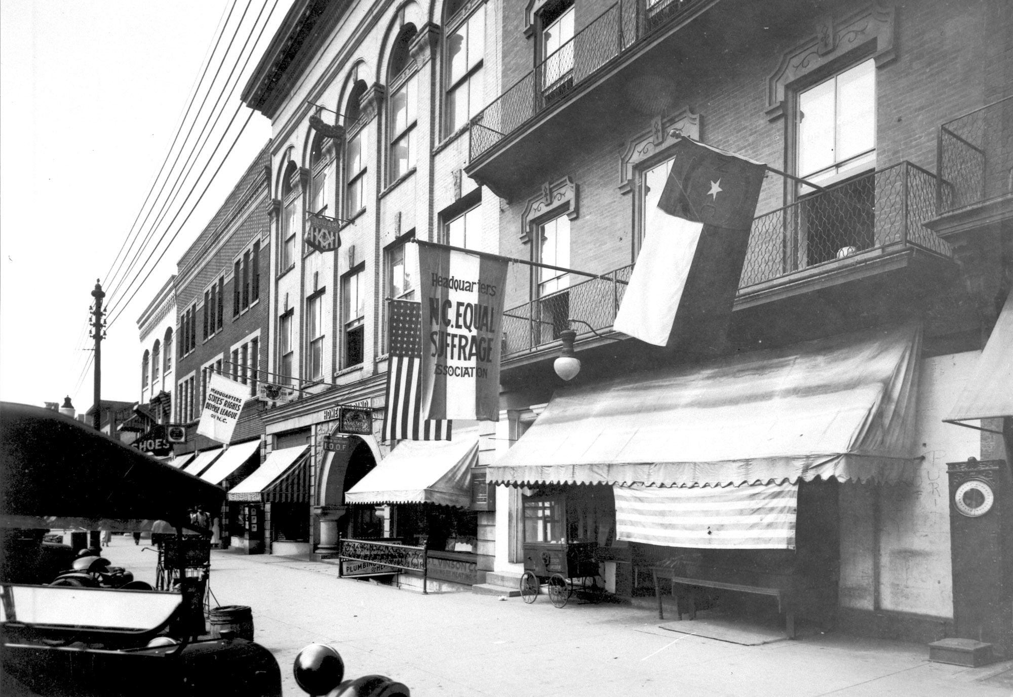 A building with a flags hanging outside, one of which reads &quot;North Carolina Equal Suffrage Association.&quot; 